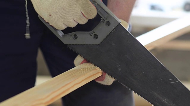 木匠用手锯近距离锯木板，在屋内修理视频下载