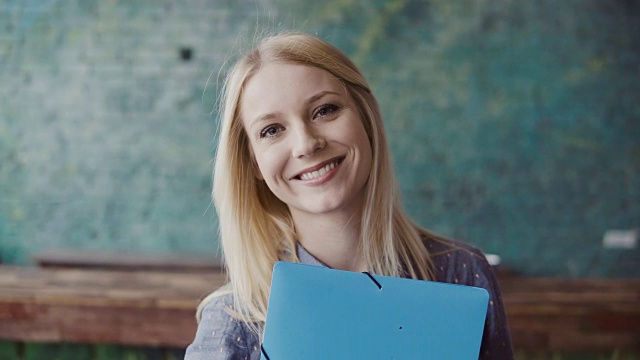 年轻白种金发女人的肖像看着照相机和微笑在现代办公室。工作上成功的员工视频素材
