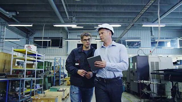 戴安全帽的工程师和工厂工人正在通过生产设施视频素材
