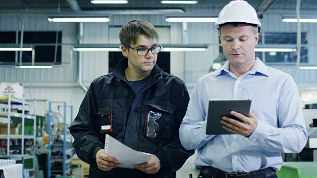 戴安全帽的工程师和工厂工人正在通过生产设施视频素材