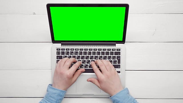 从上方的复印空间俯视男性双手在白色办公桌上用绿色屏幕的笔记本电脑工作视频素材