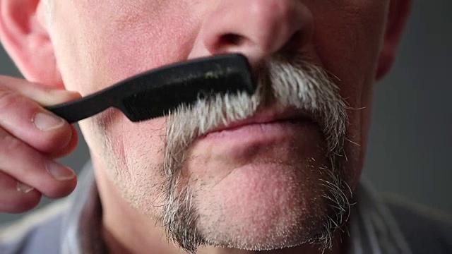 一个50多岁的男人在梳理他的胡子的特写视频下载