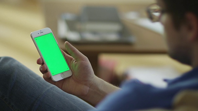 男人在家里用绿色屏幕肖像模式使用手机视频素材