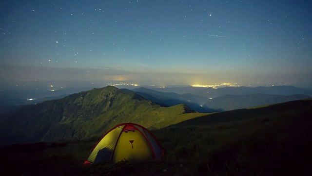 在夜晚繁星满天的背景下，月亮升起和发光的帐篷。喀尔巴阡山脉,乌克兰。视频下载