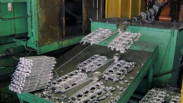 在一家汽车厂，机器人手臂正在为汽车引擎投掷冷却的金属细节视频下载