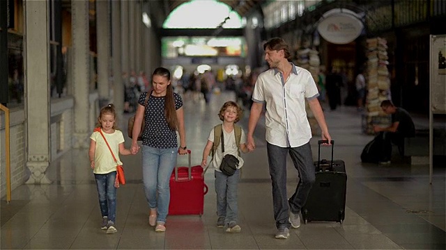 幸福的家庭带着孩子去火车站，父母和孩子们在机场旅行和行走视频素材