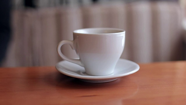 将糖倒入白色的咖啡杯中，放置在木质的背景上。视频下载