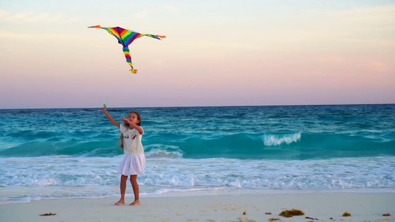 可爱的小女孩在热带海滩上放风筝。快乐的孩子在海边玩沙滩风筝。慢moion视频素材