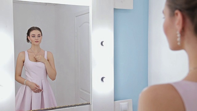 一个化妆的女人看着镜子里的自己，整理着头发视频素材