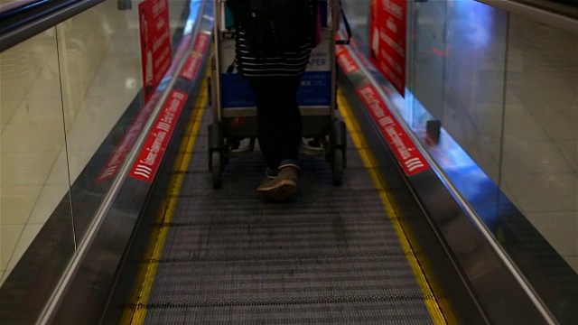 在机场航站楼的自动扶梯上携带行李的乘客。视频素材