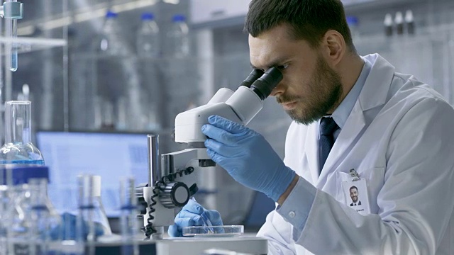 在一个现代实验室助理带来培养皿的首席研究科学家谁开始在显微镜下检查给定的样本。视频素材