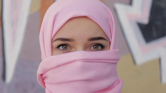 穆斯林妇女与她的头覆盖粉红色的围巾。全高清视频视频下载