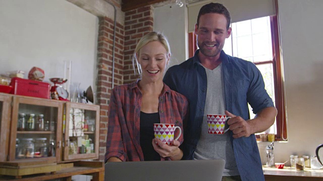 一对年轻的白人夫妇在厨房用笔记本电脑，低角度近景，用R3D拍摄视频素材