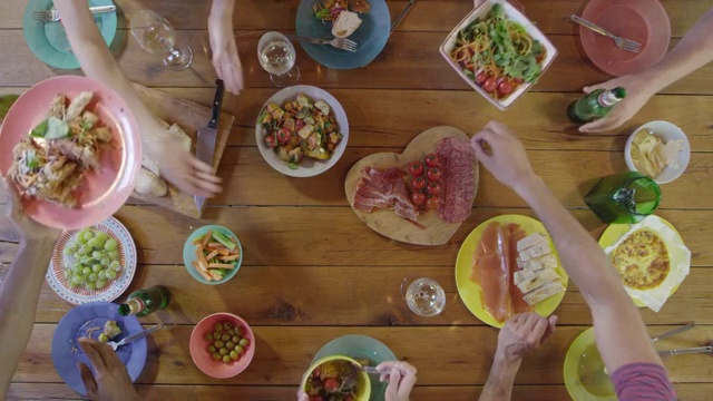 朋友们在餐桌上传递食物，在头顶上，用R3D拍摄视频素材