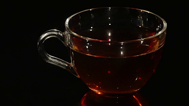 一杯茶在黑色的背景上旋转视频下载