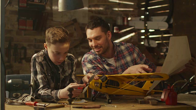 父亲和儿子正在家里的车库里制作玩具飞机。视频素材