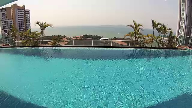 美丽清爽的蓝色游泳池水在豪华热带酒店。晴天的手掌。行动的相机视频下载