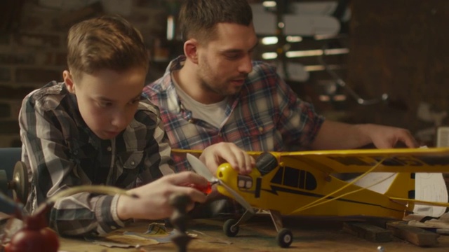 父亲和儿子正在家里的车库里制作玩具飞机。视频素材