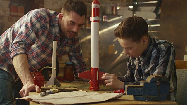 父亲和儿子正在家里的车库里制作玩具火箭。视频素材