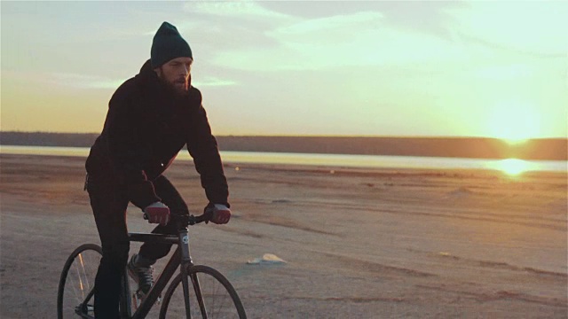 年轻英俊的潮人骑固定齿轮自行车在日落，户外视频素材