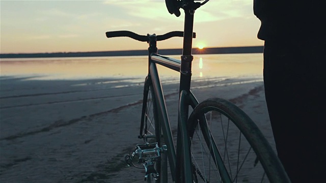 年轻英俊的潮人站在固定齿轮自行车在日落，户外视频素材