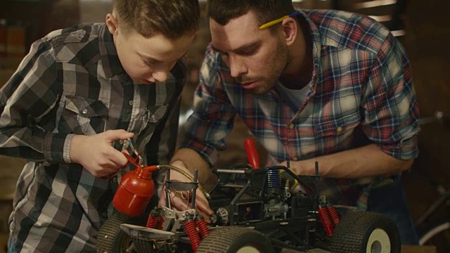 父子俩正在家里的车库里修一辆无线电控制玩具车。视频素材