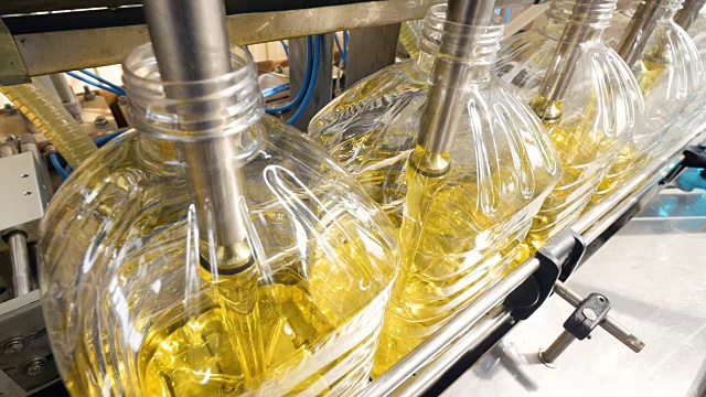 特写镜头。工厂设备倒葵花籽油的瓶子在生产线上移动。4 k。视频下载