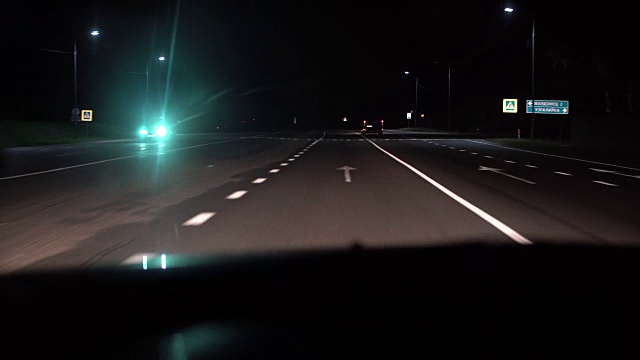 车里的夜景。车头灯和其他汽车在乡村公路上行驶视频素材