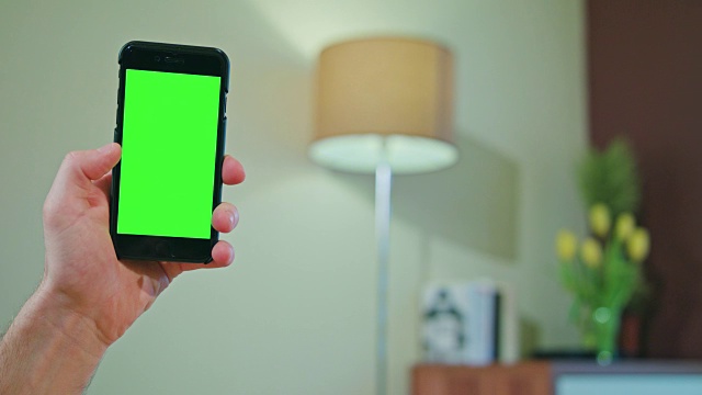 男性手持绿色屏幕的手机视频下载