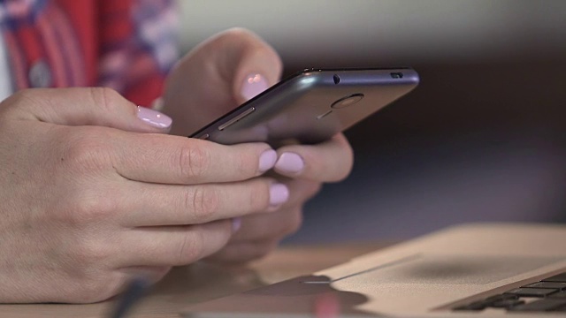 年轻女性用手在智能手机上滚动网页，女性浏览社交媒体视频素材