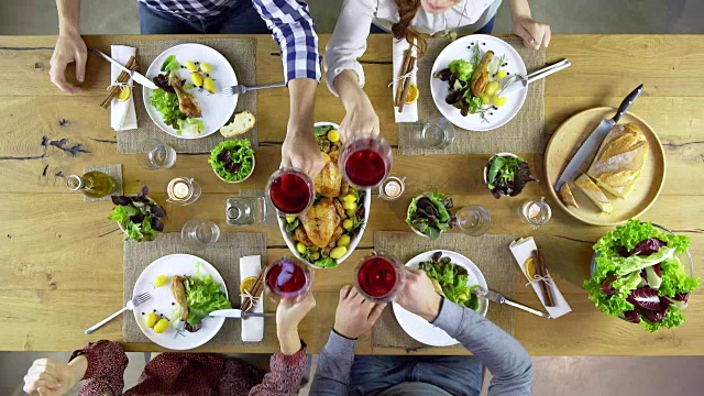 头顶顶视图表四个白种人朋友吃午餐，喝酒，一起烤鸡肉，沙拉，土豆，红酒。在现代住宅中。4 k的视频视频下载