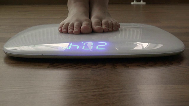 把人的腿放在地板上的电子秤上，测量你的体重视频素材
