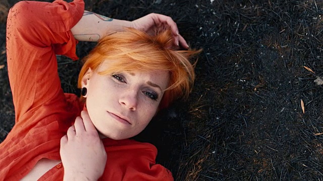 那个红头发的悲伤女孩躺在黑黝黝的地上，忧伤地望着天空。概念:需要帮助，寂寞视频素材