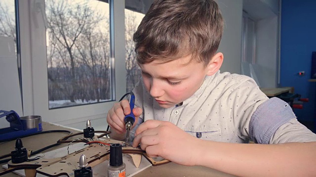 男孩在学校实验室组装无人机和直升机。替身,4 k。视频下载