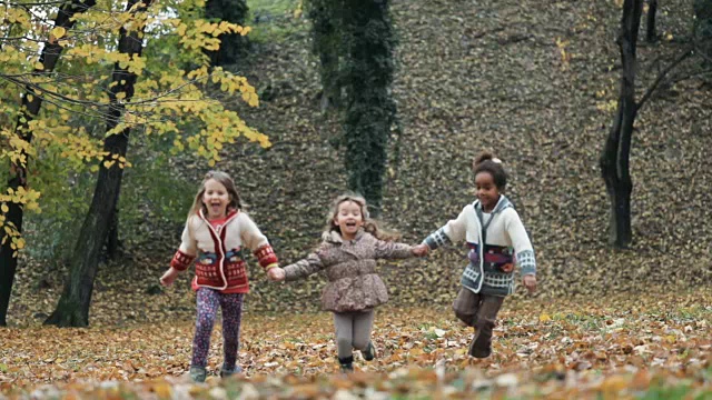 秋日里，小朋友们手牵着手在公园里嬉戏。缓慢的运动。视频素材