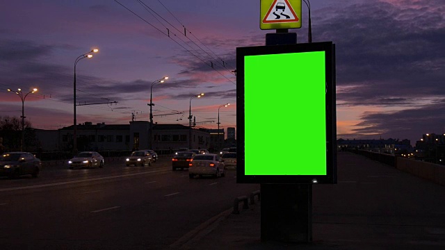 一个在繁忙的街道上有绿色屏幕的广告牌。视频素材