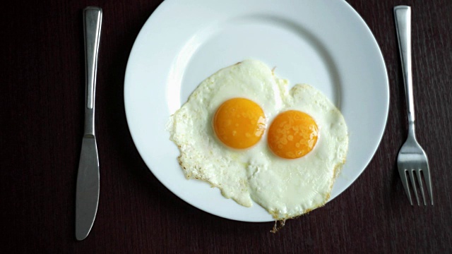 木桌上的白色盘子和煎蛋。供应早餐的鸡蛋视频素材