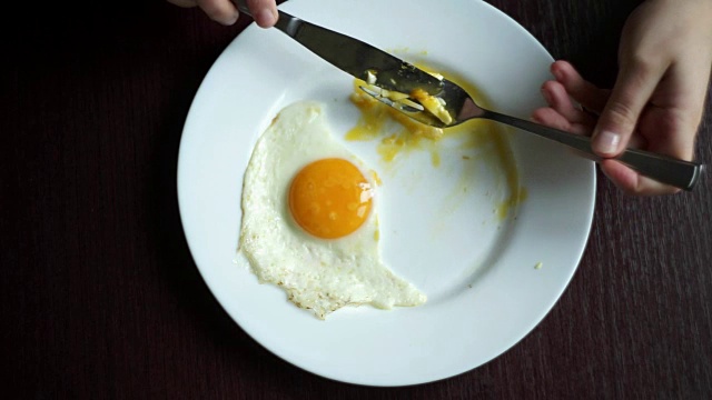 俯视图手用刀叉在盘子上吃煎蛋视频素材
