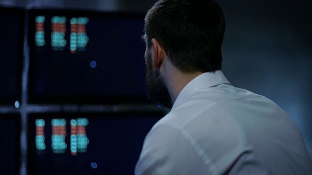 深夜交易员在他的多重显示器上读取股票信息的数字。在背景大城市窗口视图。视频素材
