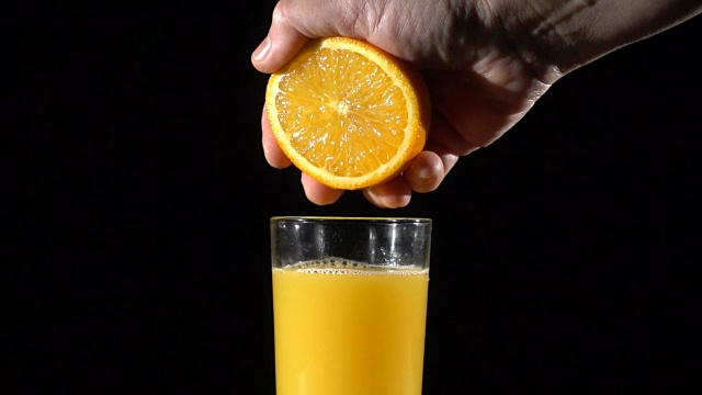 人们的手把橙汁挤在杯子里，慢吞吞的视频素材