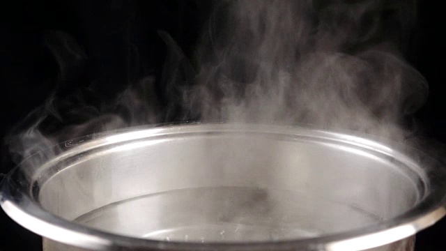 开水在黑色背景的钢锅上，慢动作视频下载