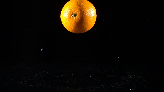 落下的橙色水果在黑色背景，慢镜头视频素材