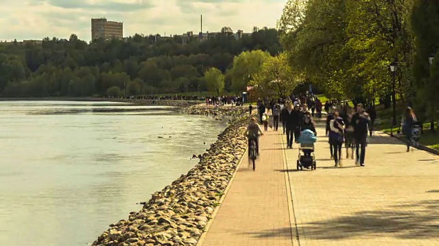 随着时间的流逝，人群沿着城市河堤散步视频素材