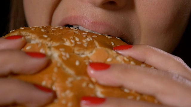 慢镜头近距离饥饿的年轻女子吃垃圾食品、不健康的快餐、三明治、汉堡包视频素材