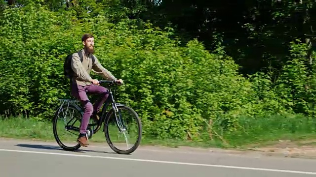 侧视图-一个年轻人骑自行车。享受这次旅行。在春天绿树的映衬下视频素材