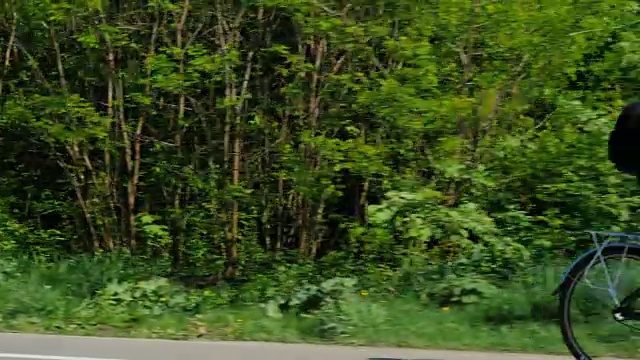 一个骑自行车的人出现在空框中。他骑自行车，背景是一片绿色的森林。良好的春天视频素材