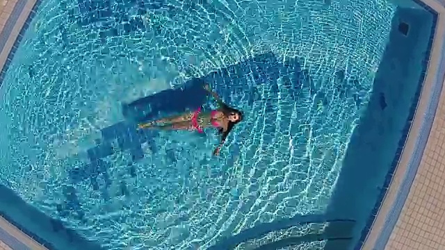 迷人的女人在蓝色的池子里游泳视频素材