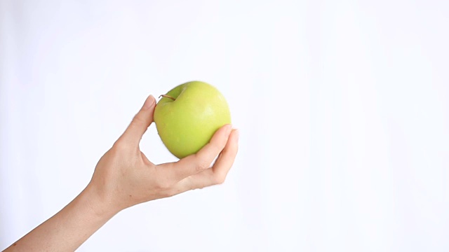 女性的手拿着一个绿苹果在白色的背景视频下载