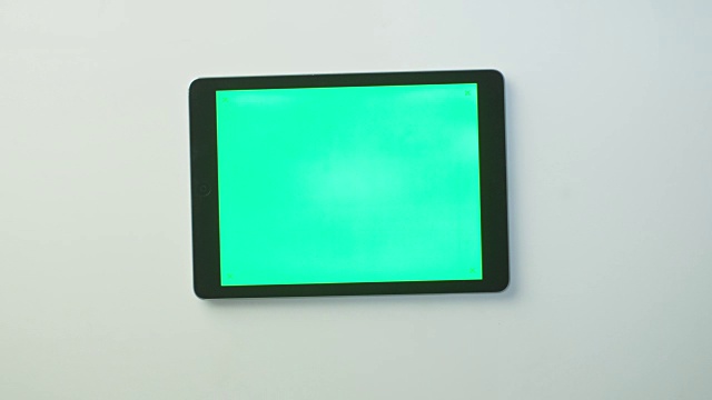 手把绿色屏幕的平板电脑放在白色的桌子上并开始使用它。伟大的模型使用。视频下载