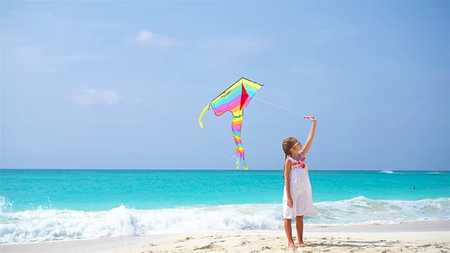 小女孩在热带海滩上放风筝。孩子们在海边玩耍。有沙滩玩具的孩子。视频素材